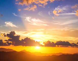 Stunning golden sunset illuminates majestic mountain range with ethereal clouds, creating a peaceful and inspiring landscape perfect for travel and adventure themes