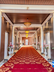 Wedding entrance hallway with floral decor, chandeliers and carpet, suitable for event venue and celebration themes.