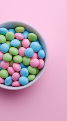 Obraz premium A bowl is filled with pastel-colored candy pieces on a pink surface. 