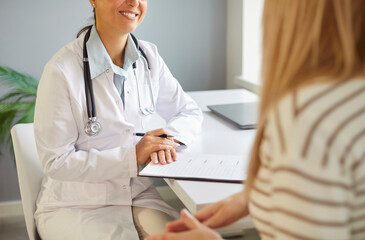 Cropped image of unrecognizable professional female doctor gives consultation to woman patient who...