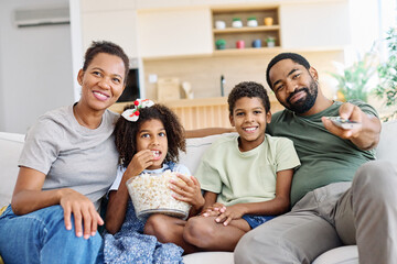 Portrait of a happy black family mother father and kids at home on couch