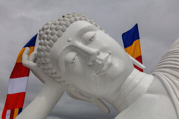 Closeup of giant white reclining Buddha statue at Dharma Giri Vihara temple, in northern Bali. Cloud sky as a backdrop.

