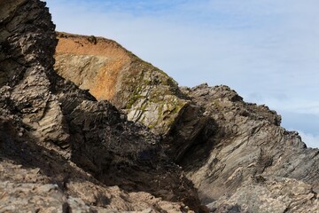 Rocky cliffs with layers of different colored stone are shown in Polly Joke - Cornwall - UK