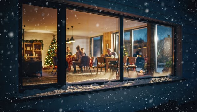 Family enjoys a festive Christmas dinner together around a warmly lit dining table inside a modern home while snow falls outside.