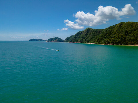 Aerial view of Pantai Bukit Keluang, Besut, Terengganu, showing turquoise waters, coastal cliffs, and clear sunny skies along the scenic shoreline.