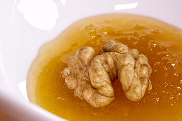 Peeled walnut soaked in a vessel with natural honey, macro shot.
