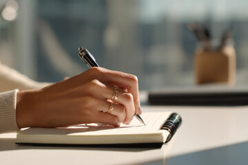 Close-up of a woman's hands writing in a notebook