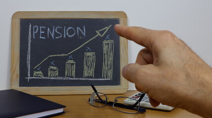 Man's hand points to pension writing on vintage chalkboard with positive business graph.
