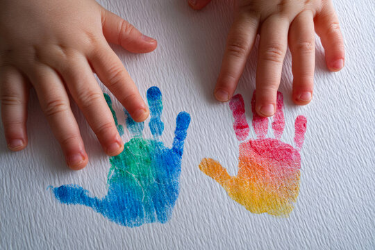 A child leaves handprints with paint on paper