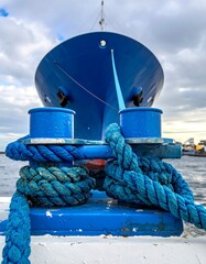 Close-up of a blue ship's bow and knotted mooring rope