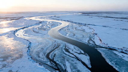 Aerial drone view of a majestic winding frozen river and intricate ice patterns through a vast snowy winter landscape at sunrise, showcasing the serene beauty of cold nature.