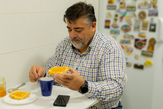 Mature man enjoying morning breakfast with jam and coffee