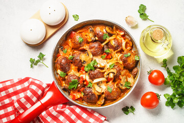Meatballs with mushrooms in tomato sauce in a frying pan.