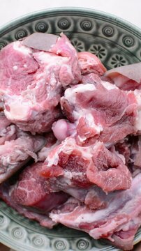 overhead view of Fresh raw goat meat in a bowl, top view of chopped goat meat being prepared for cooking