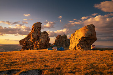 Beautiful sunset landscape with big stoned formations and tourist camp at sunset mountain top