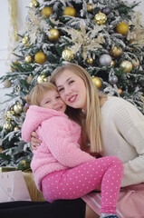 mom and daughter happily playing and having fun near the Christmas tree