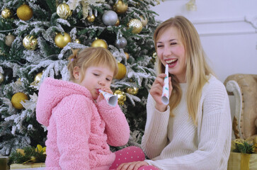 mom and daughter happily playing and having fun near the Christmas tree