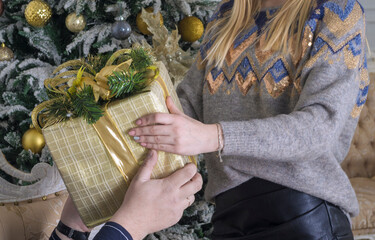 a young woman hands a box . wrapped in gift paper , a gift to a man