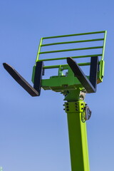 Forklift loader or stacker on blue sky background. Hydraulic and pneumatic mechanism in machine. Technology in transport