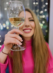 a beautiful young woman is drinking sparkling wine in a glass, celebrating and having fun
