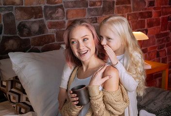 mom plays on the big bed in the bedroom with her daughter and reads a book to her