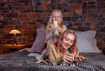 mom plays on the big bed in the bedroom with her daughter and reads a book to her