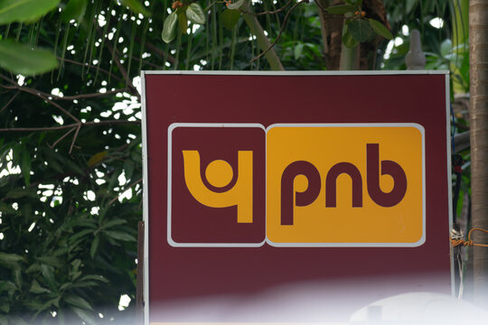 A Punjab National Bank signboard set against greenery, representing retail banking, finance, deposits, loans, urban architecture, city heritage, commercial activity, regulation, RBI