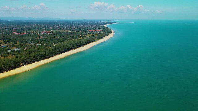 Aerial view of Pantai Bukit Keluang, Besut, Terengganu, showing turquoise waters, coastal cliffs, and clear sunny skies along the scenic shoreline.