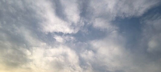 Background with clouds on blue sky. Sky view. Beautiful sunny sky. Clouds on blue sky. Sun shining through the puffy clouds.
