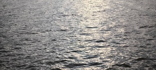 Water ripple texture background. Wavy water surface during sunset.