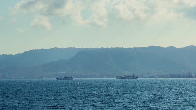 Bali, Indonesia - August 27, 2025: Car and passenger ferries cross the Bali Strait from Gilimanuk Harbor to Ketapang Harbor on the island of Java. View of the strait from the ferry deck. 4K