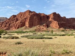Fototapeta premium Red Water Valley, surrounded by tall sandstone cliffs and rugged desert terrain, Kyrgyzstan.