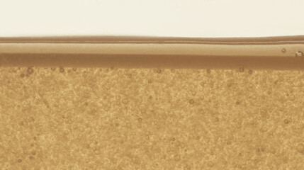 bottle of yellow hair oil, shampoo, cleanser, macro texture of oil with bubbles, cosmetic textures, skincare product liquid