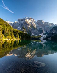 Calm lake reflects rugged mountains under a clear, bright blue sky