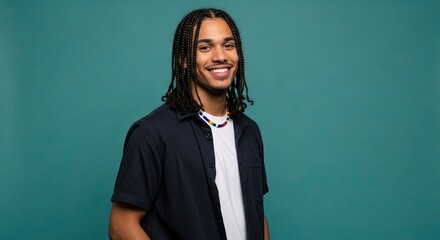Smiling young man with dark braided hair and a white t-shirt under an open navy shirt