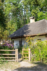 Rural peasant house surrounded by blooming flowers and trees in a serene countryside setting