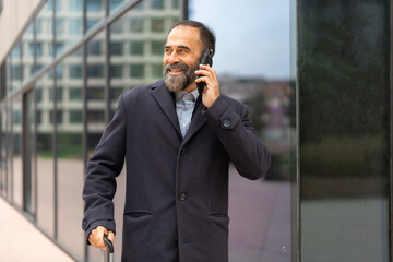 Mature businessman actively talking on smartphone during business travel