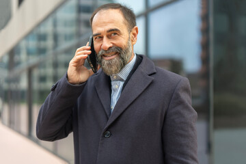 Senior man smiling while talking on smartphone in city