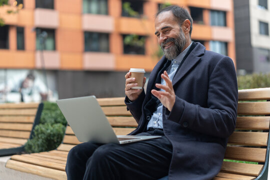 Mature man having video call on laptop outdoors
