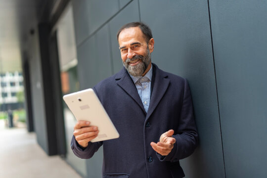 Mature businessman holding tablet smiling discussing solution