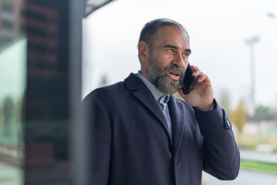 Mature businessman talking on mobile phone outdoors - Powered by Adobe