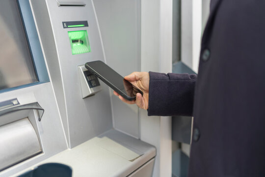 Person using smartphone for contactless atm transaction