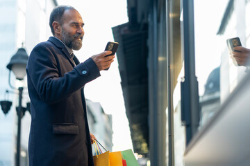 Mature man shopping, smiling and using smartphone