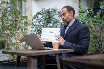 Mature businessman presenting data during outdoor video conference
