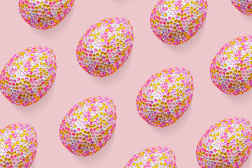 Sparkling easter eggs as creative pattern on pastel pink. Minimalist contemporary design, abstract aesthetic food. Decorative colorful eggs with rhinestones or sequins as easter holidays background.