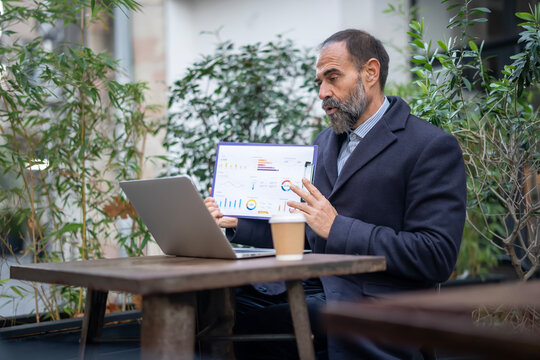 Mature businessman presenting data during outdoor video conference