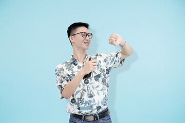 young asian man surprisingly look at his watch concept of rushing and late in blue studio background