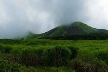 Lush green hillsides around Mt. Aso close to Nakadake Crater with views on the cone of Komezuka crater and other peaks, Kumamoto, Japan