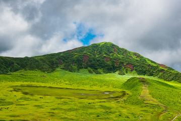 Lush green hillsides around Mt. Aso close to Nakadake Crater with views on the cone of Komezuka crater and other peaks, Kumamoto, Japan
