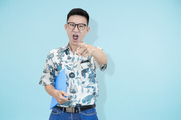Excited Asian individual pointing forward, holding a blue folder, signifying a direct challenge or...